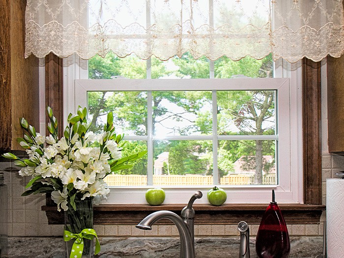 Kitchen window above the sink with a sheer white valance.